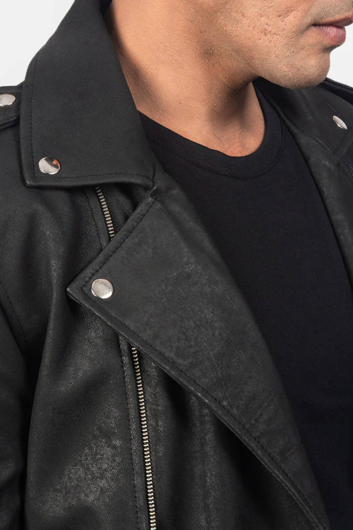 Close-up of a person wearing a black leather jacket with a zipper.