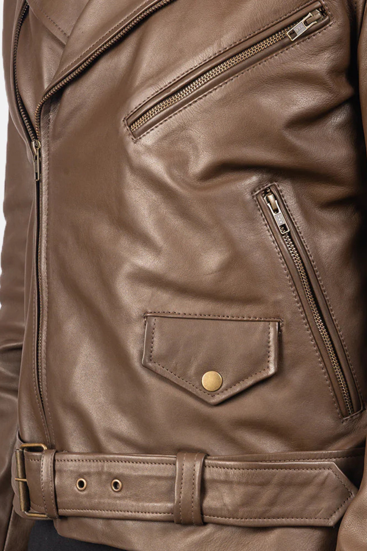 Close-up of a brown leather jacket with zippers and a button.