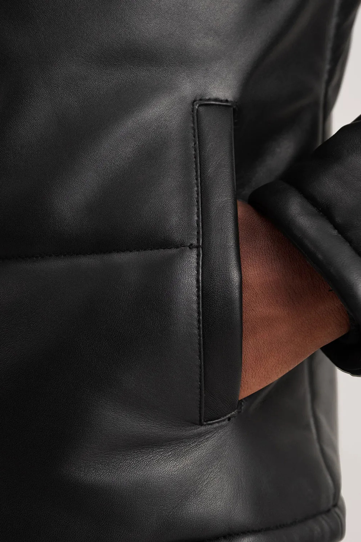 Close-up of a black leather jacket with a brown interior lining.