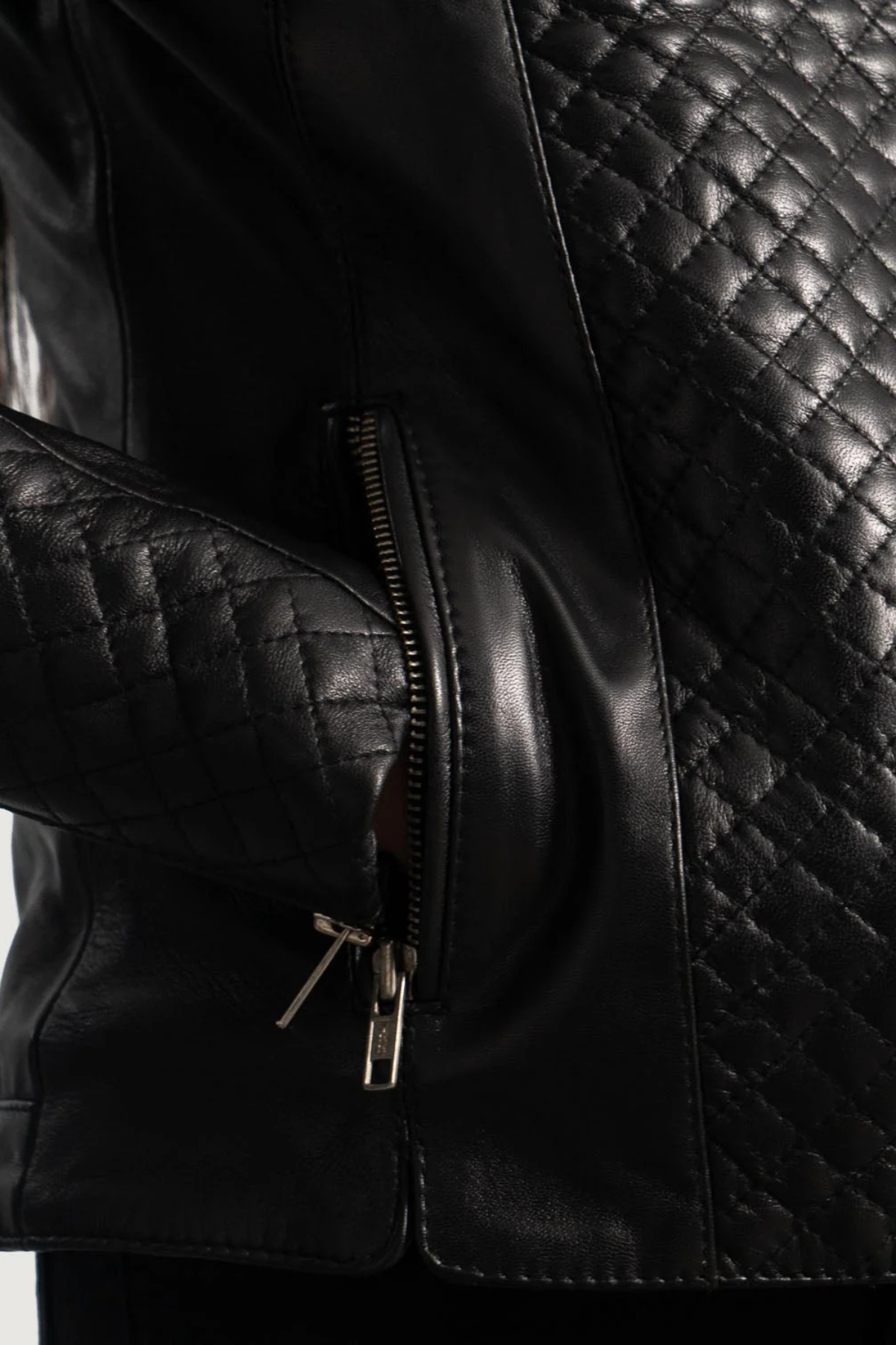 Close-up of a black quilted leather jacket with a zipper.