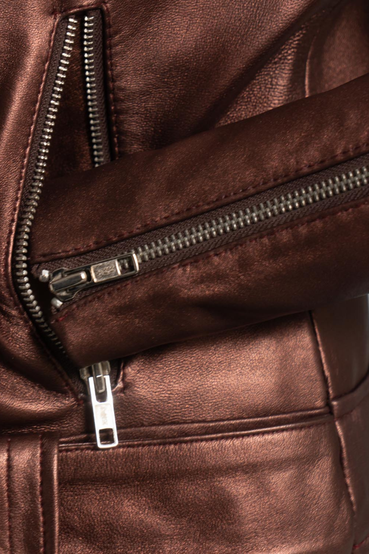 Close-up of a brown leather jacket with zippers