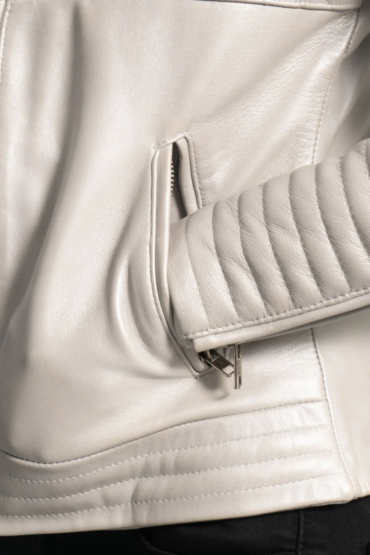 Close-up of a light gray leather jacket with a zipper detail.